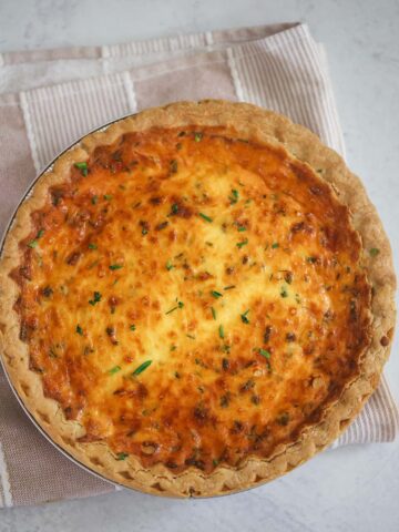 Three cheese quiche on a pink and white towel.