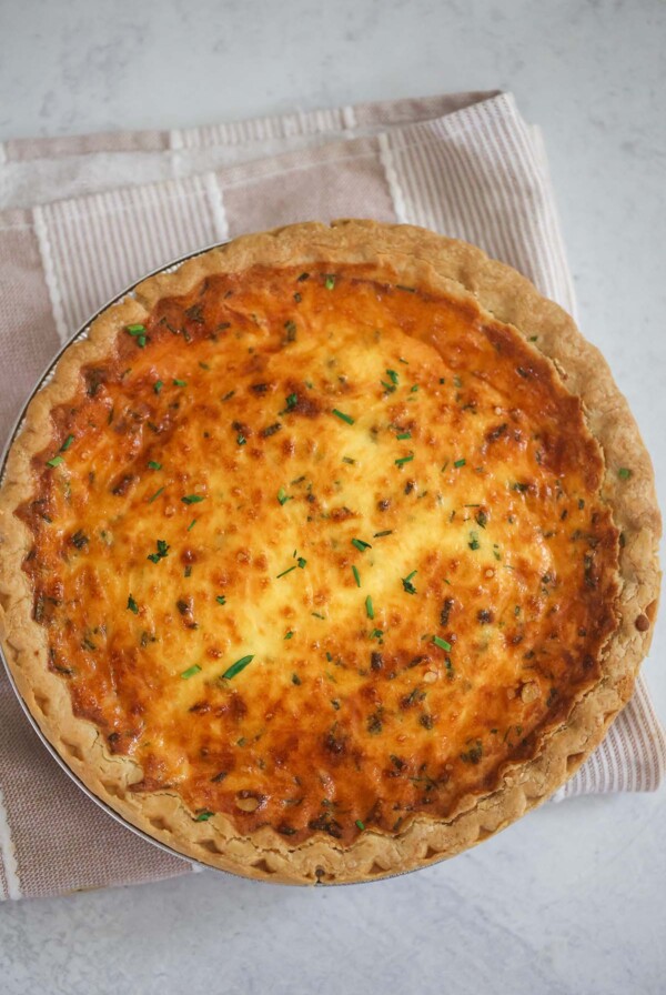 Three cheese quiche on a pink and white towel.