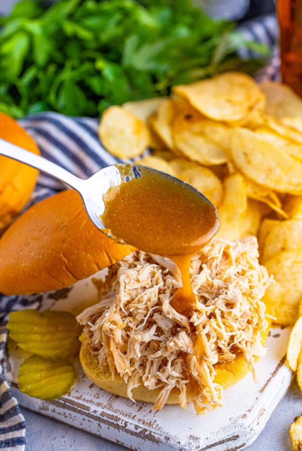 Nashville chicken sandwich with chips and pickles on the side.