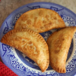 Three ground beef empanadas on a blue plate.