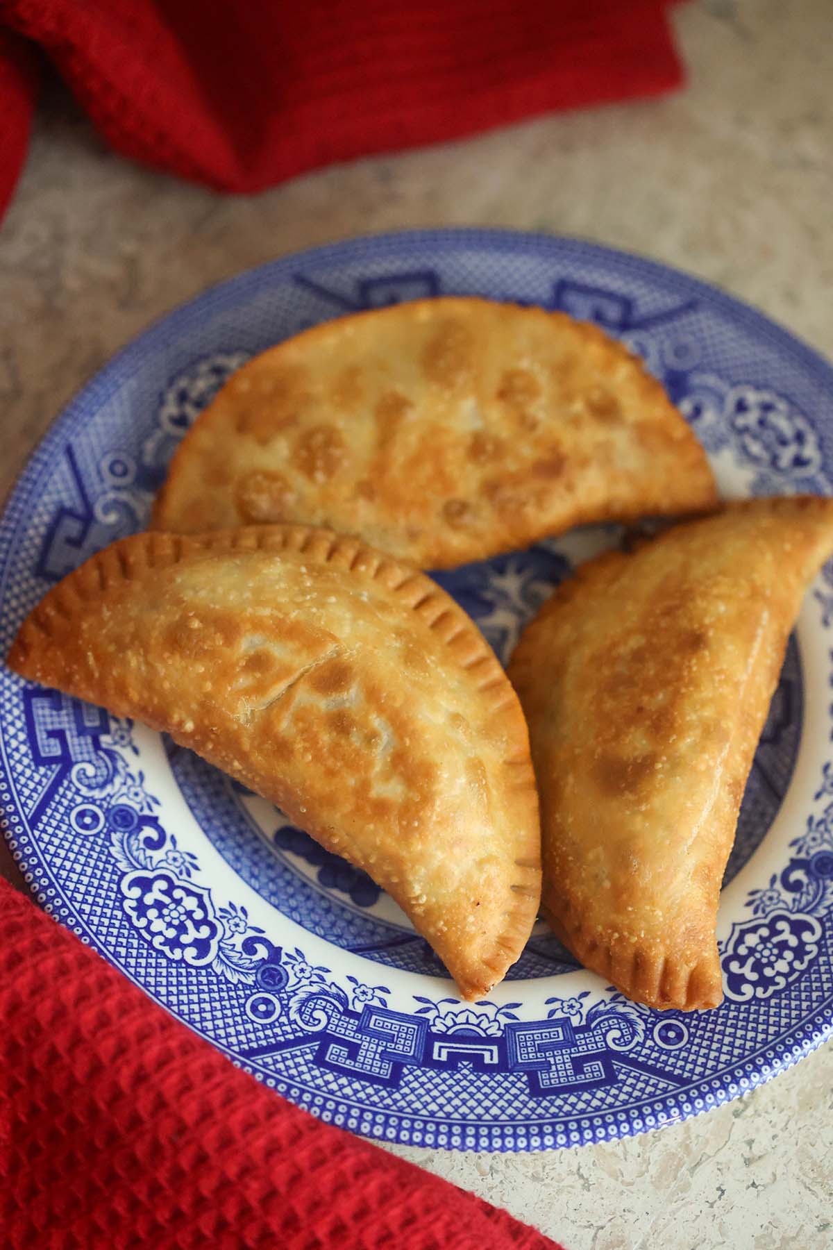 Three ground beef empanadas on a blue plate.