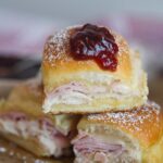 Three monte cristo sliders on a cutting board.