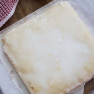 white chocolate lemon blondies on a cutting board with a lemon on the side.