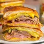 Cuban sandwich sliced in half on a white plate.