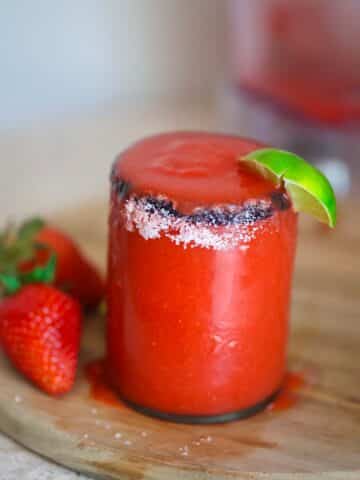 frozen strawberry margarita in a glass with salt on the rim.