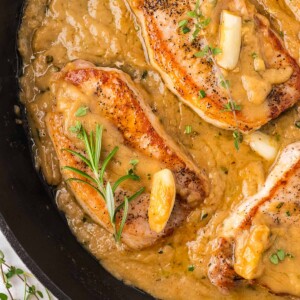 pan seared pork chops with gravy in a cast iron skillet.
