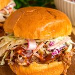 Pulled pork sandwich with coleslaw on top.