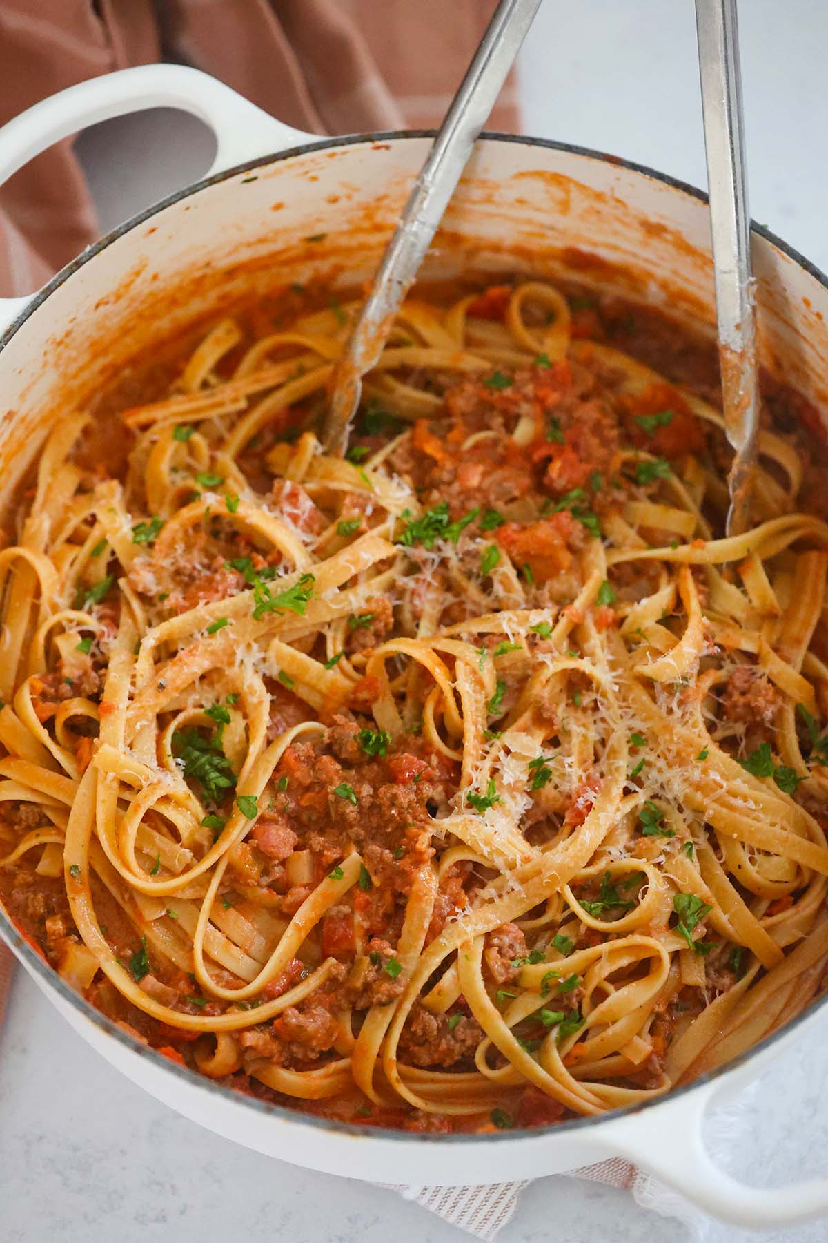 Pasta in a large pot with tongs.
