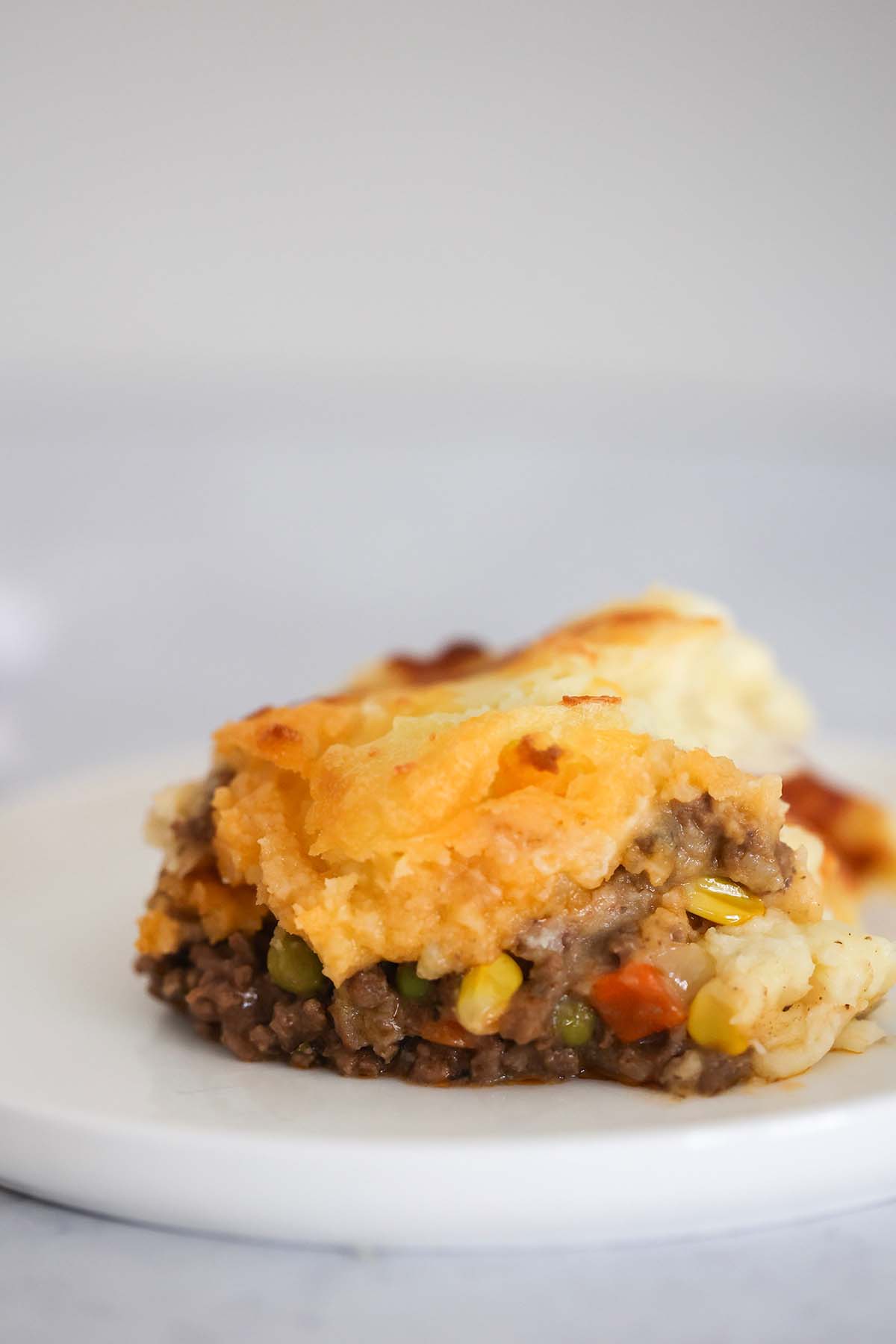 A slice of cottage pie on a white plate. 