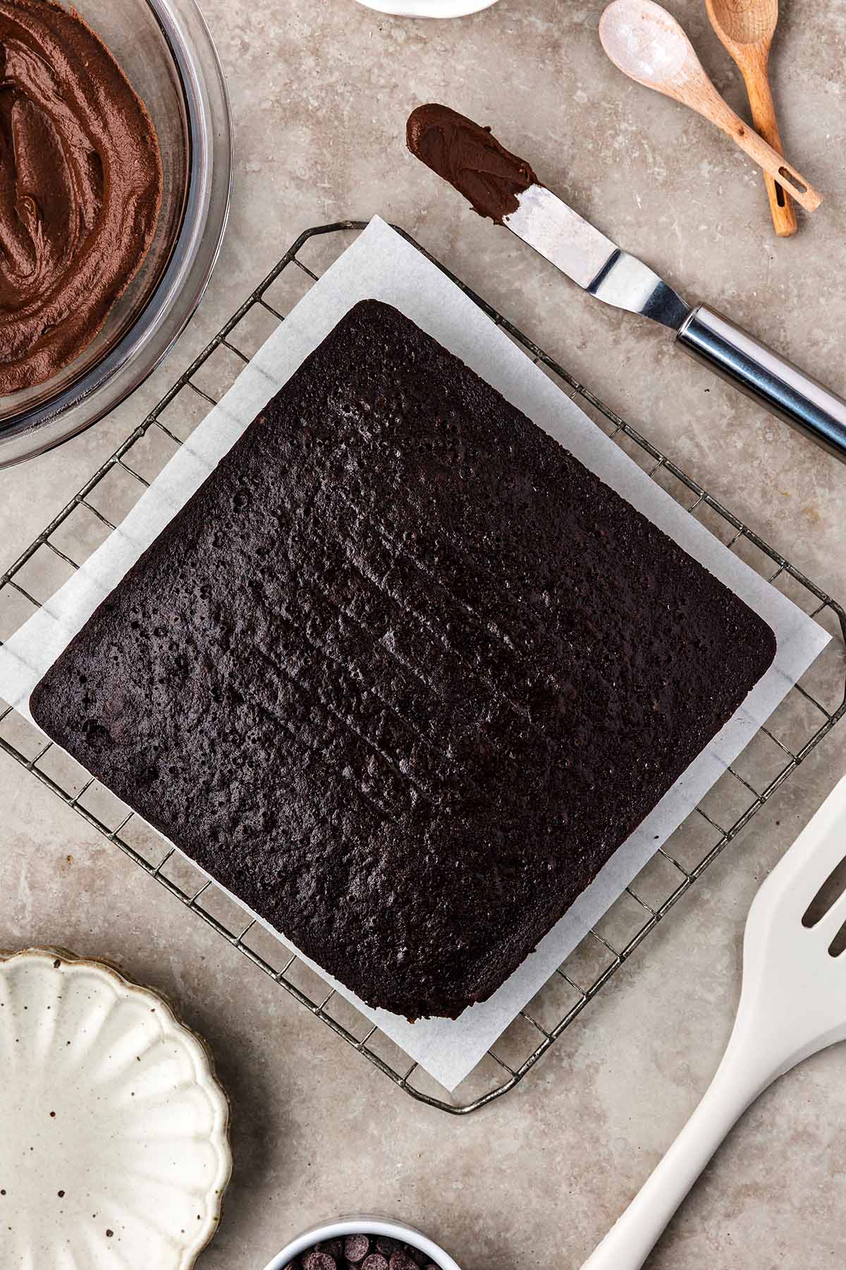 8x8 inch baked cake with a bowl of chocolate frosting on the side. 