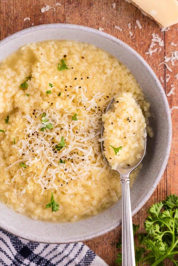 A bowl of pastina with parmesan cheese and parsley on top.