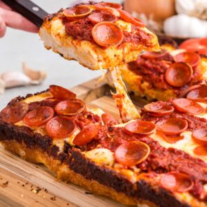 Detroit style pan pizza on a cutting board.