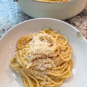 Buttered noodles in a bowl and a skillet in the background.