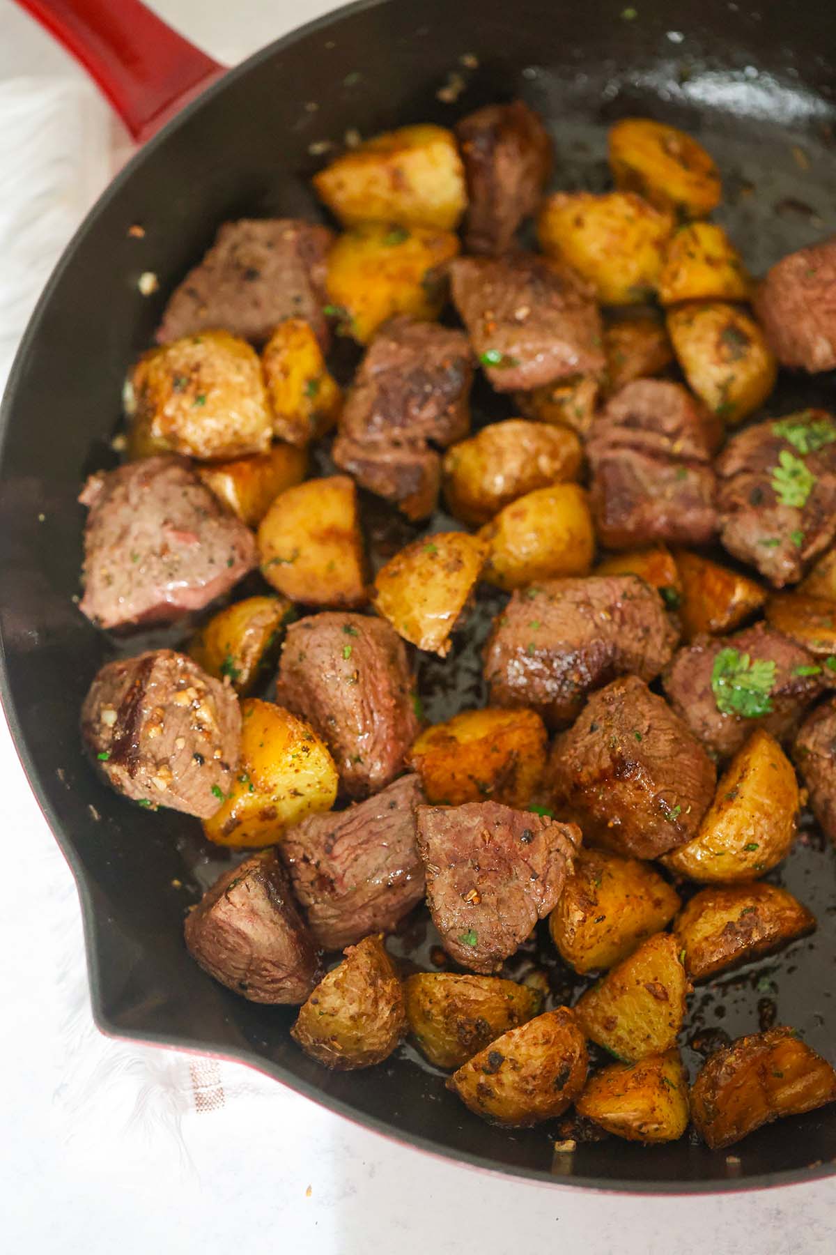 Steak bites and potato cubes in a skillet.