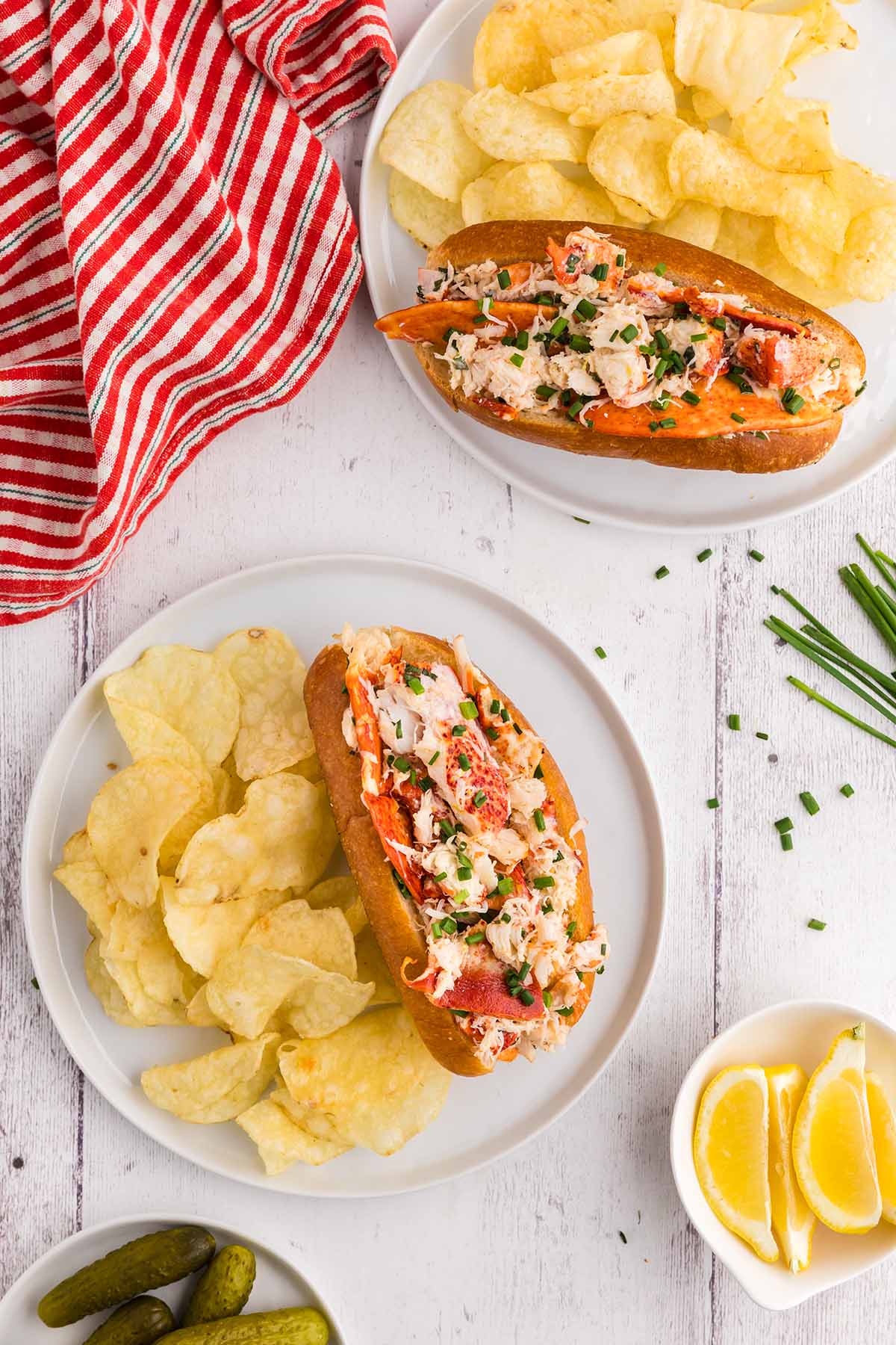 Two lobster rolls with potato chips on the side.