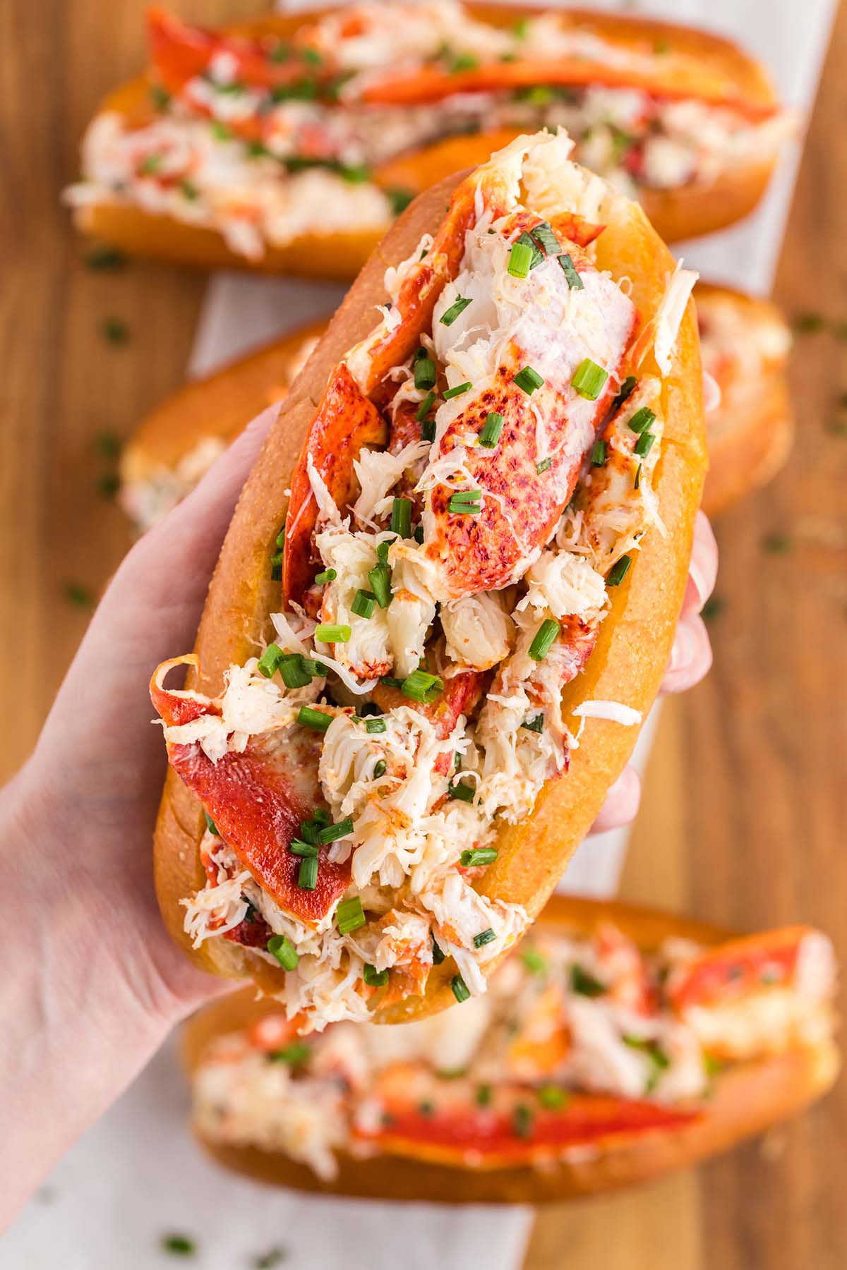 A hand holding a lobster roll up close.