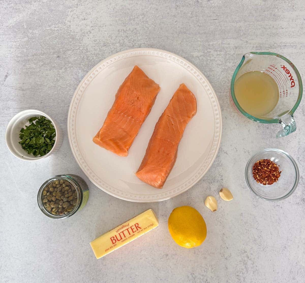 Two salmon fillets, chicken stock, garlic, parsley, capers, lemon, butter, and red pepper flakes. 