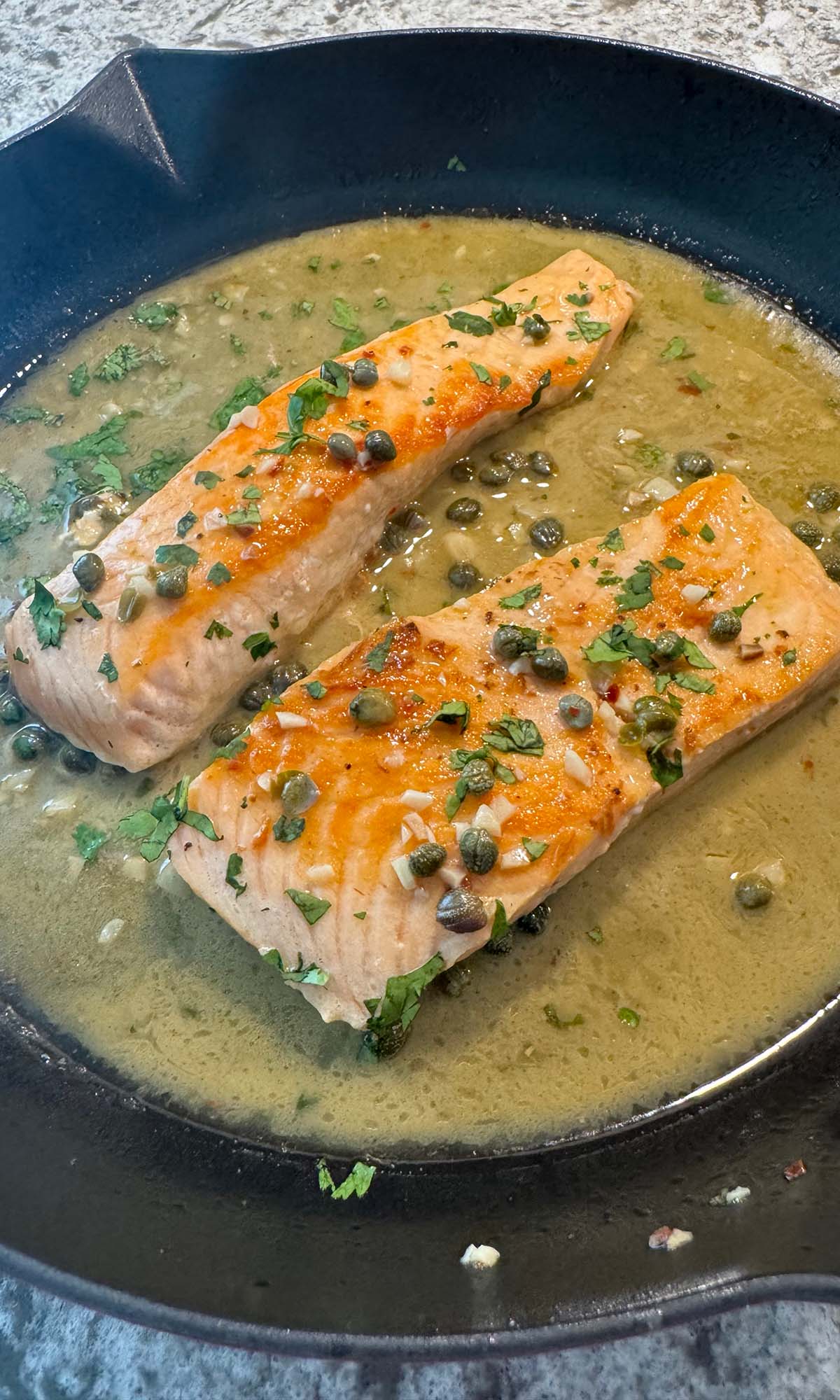Salmon piccata in a cast iron skillet.