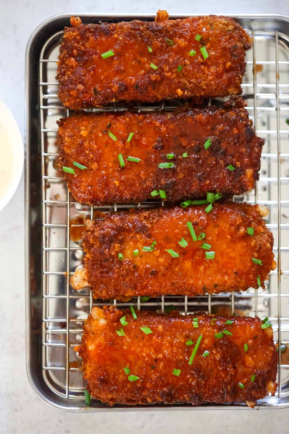 Four honey chipotle fried mozzarella sticks on a rack.