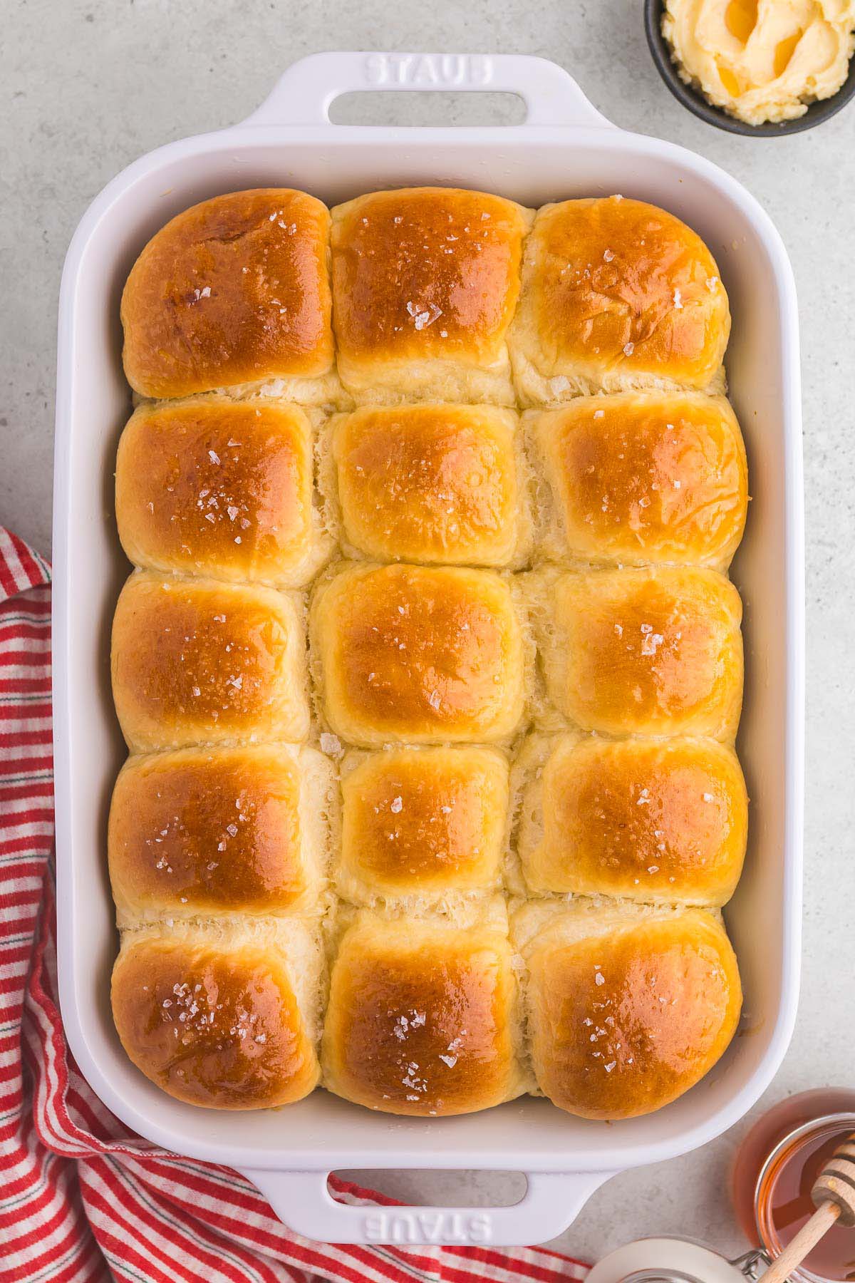 15 baked parker house rolls in a 9x13 white baking dish.