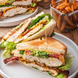 A chicken club sandwich with French fries on the side.