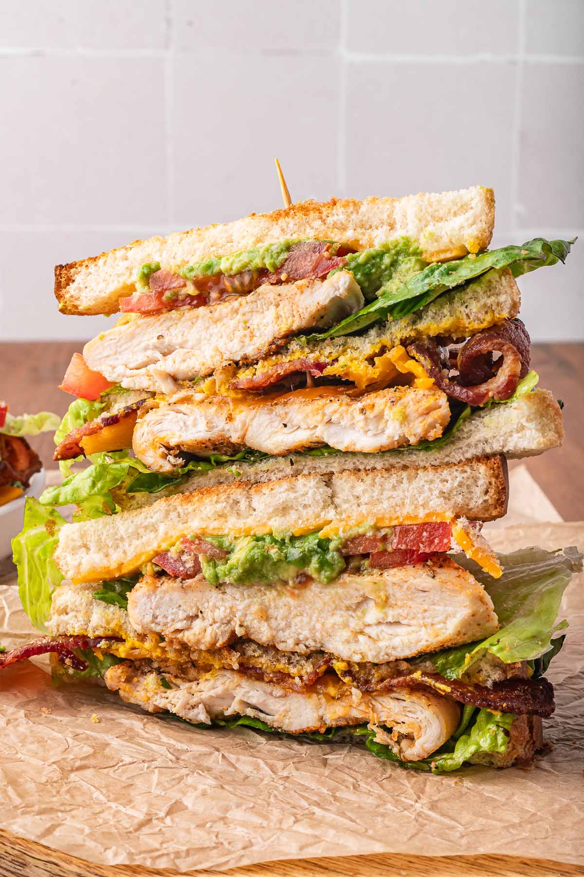 chicken club sandwiches stacked on a cutting board. 