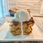 A slice of bread pudding with a scoop of vanilla ice cream on top.