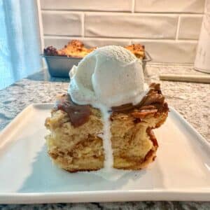 A slice of bread pudding with a scoop of vanilla ice cream on top.