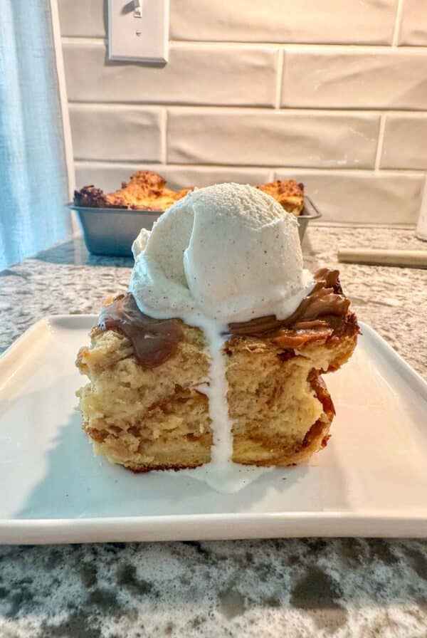 A slice of bread pudding with a scoop of vanilla ice cream on top.