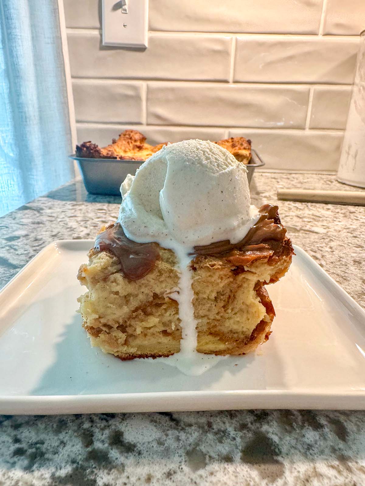 A slice of bread pudding with a scoop of vanilla ice cream on top.