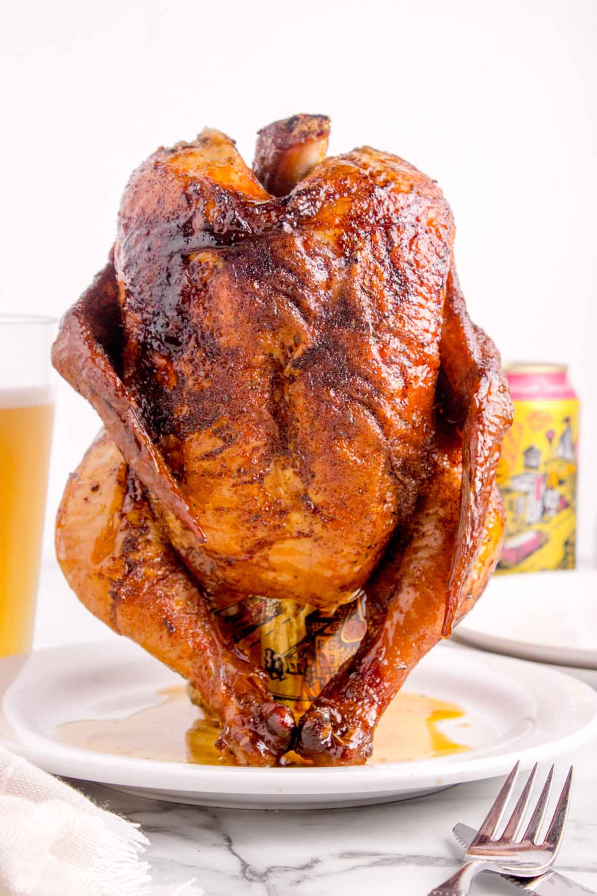 A fully cooked whole chicken on a white plate. 