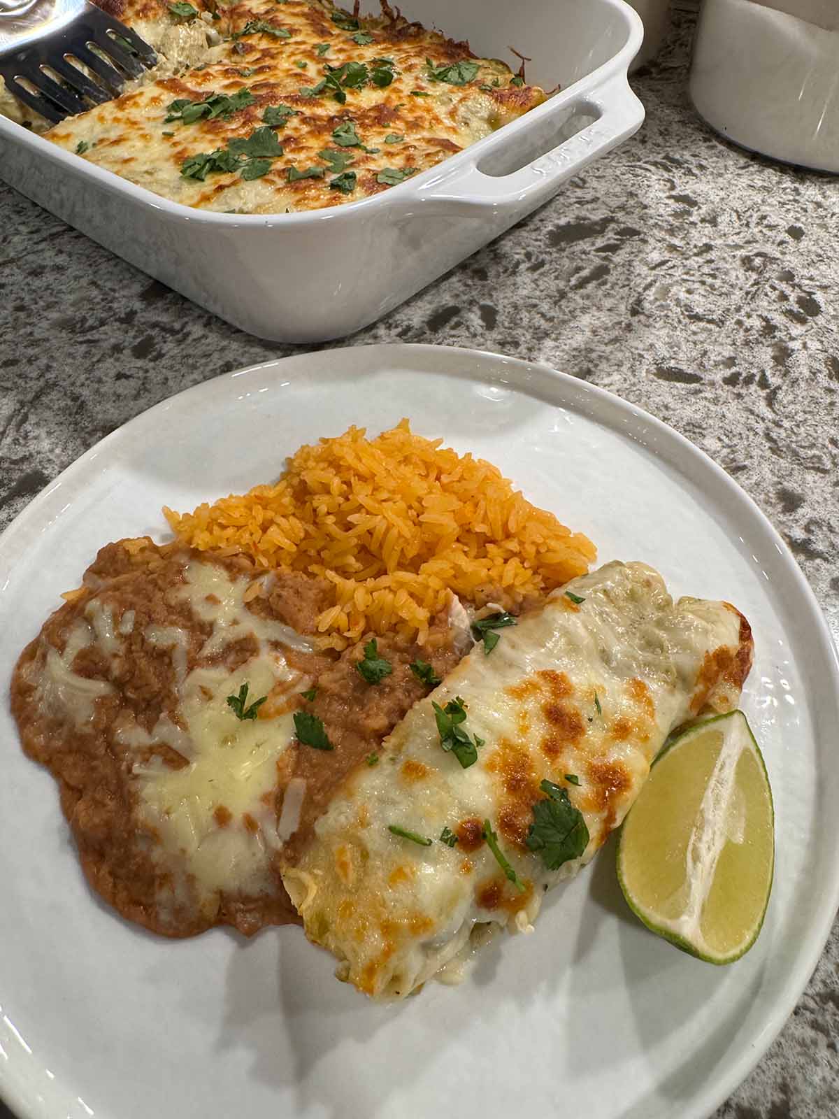 Green Chile chicken enchiladas with yellow rice and refried beans. 