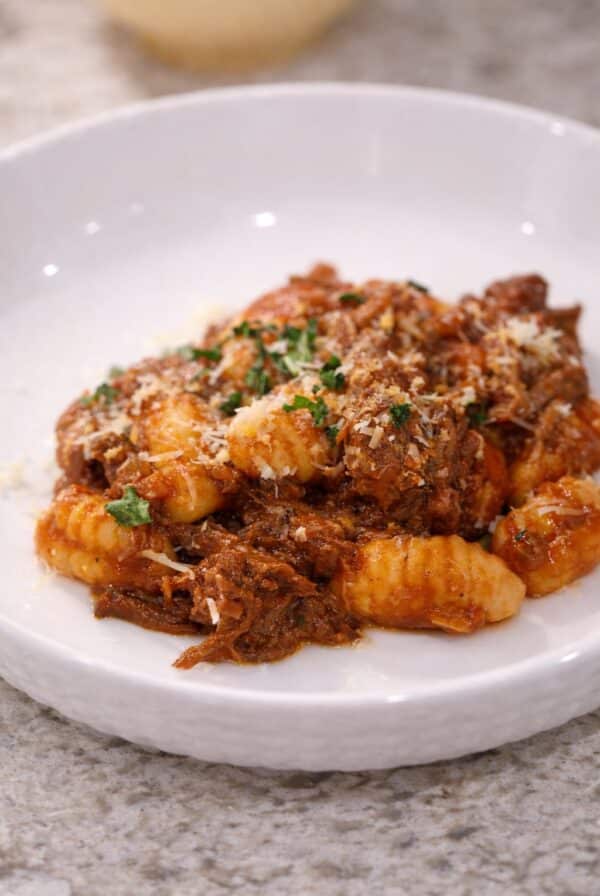 Braised beef with gnocchi in tomato sauce, topped with parmesan and parsley.