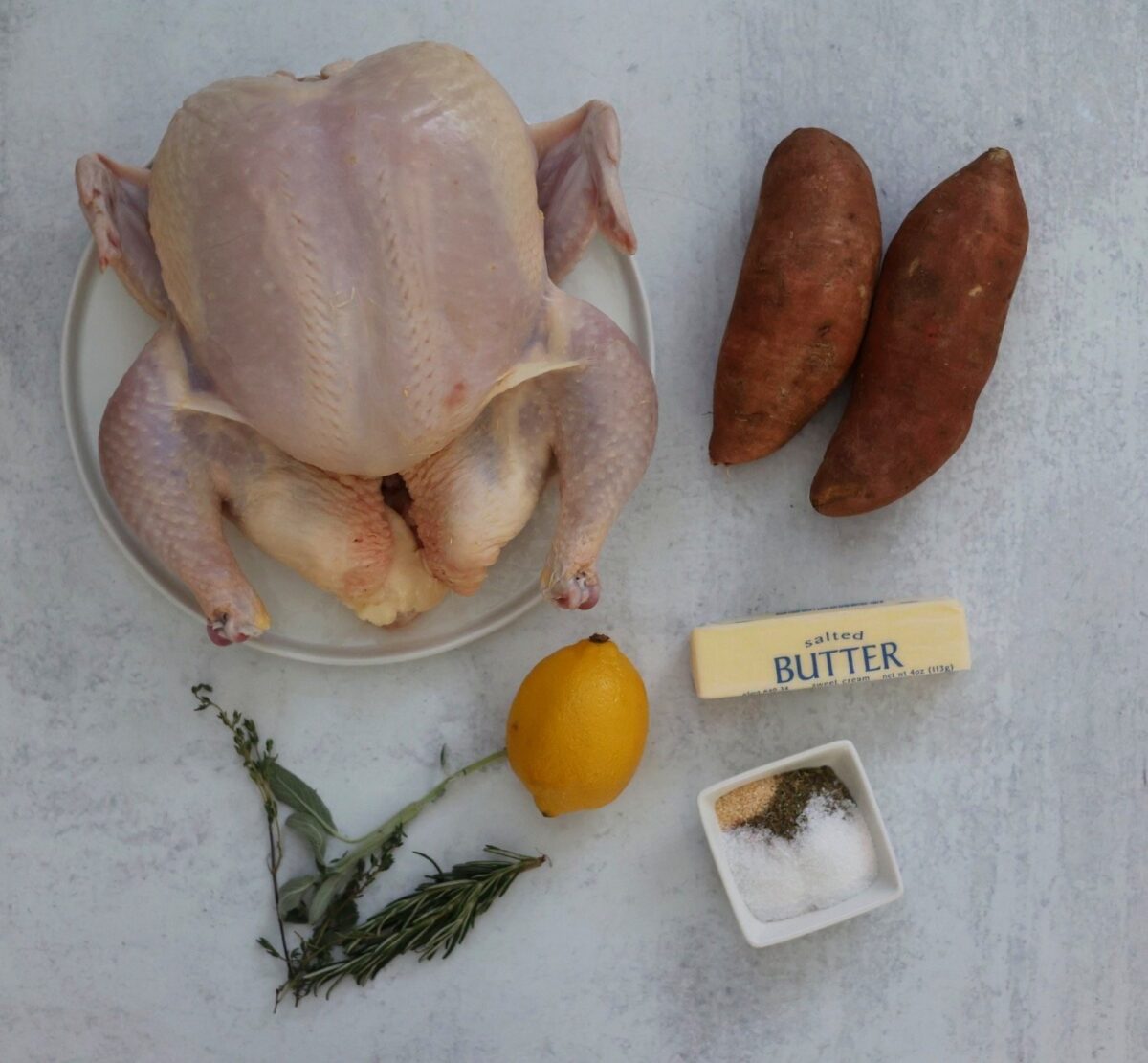 Whole chicken, sweet potatoes, spices, butter, lemon, and herbs.