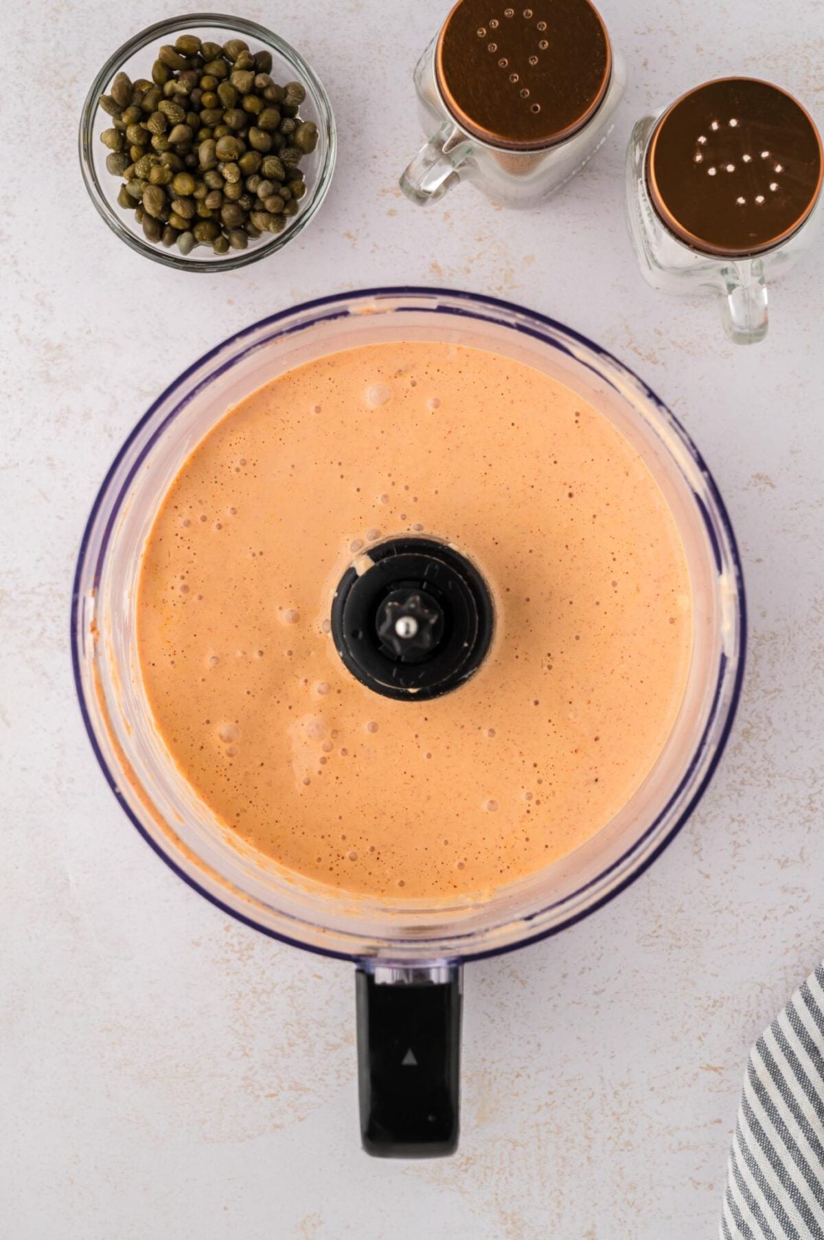 remoulade sauce in a food processor with capers and salt and pepper on the side.