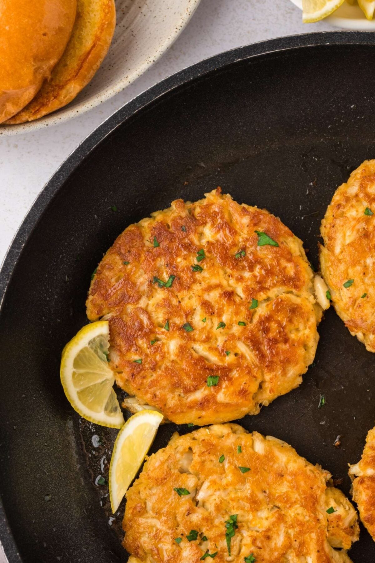 Cooked crab cakes in a black skillet.