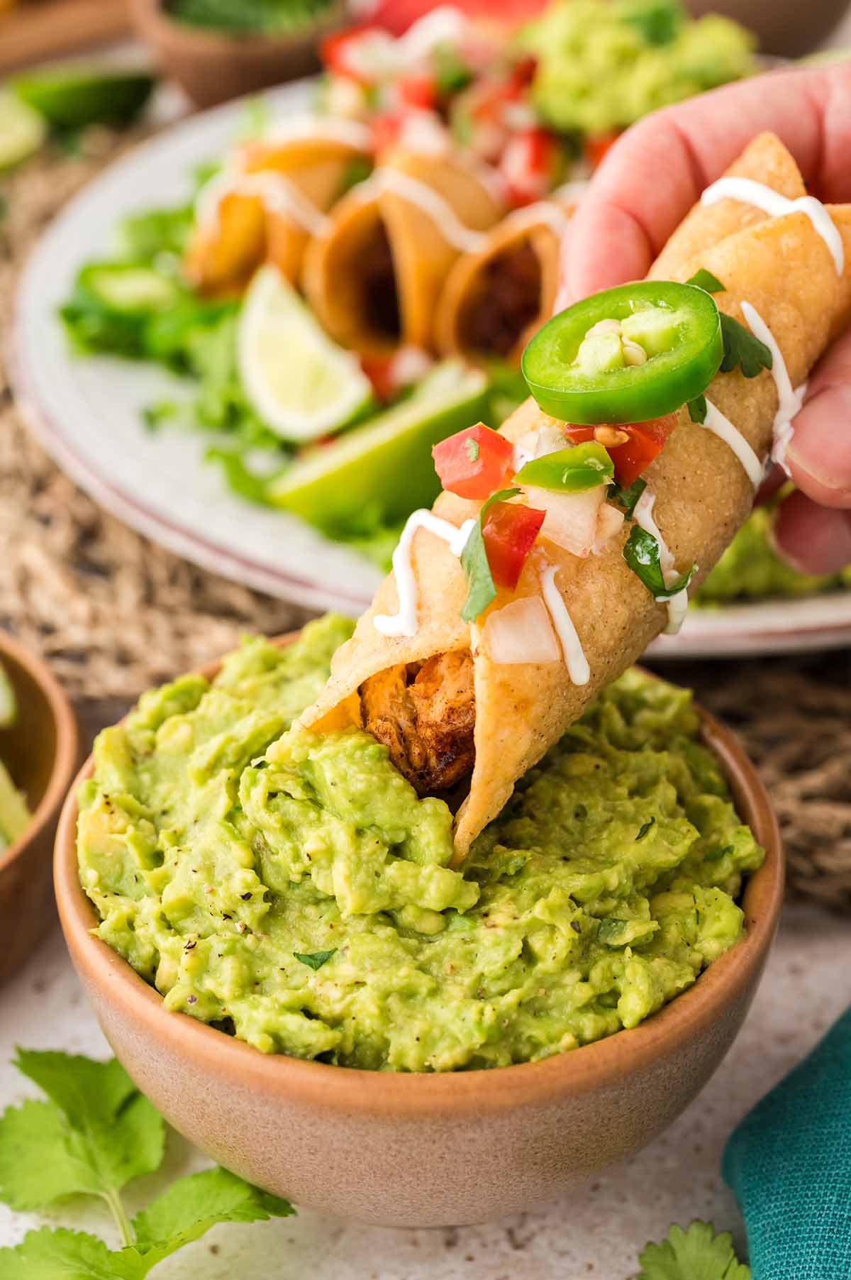 chicken flauta dipped in a bowl of guacamole.