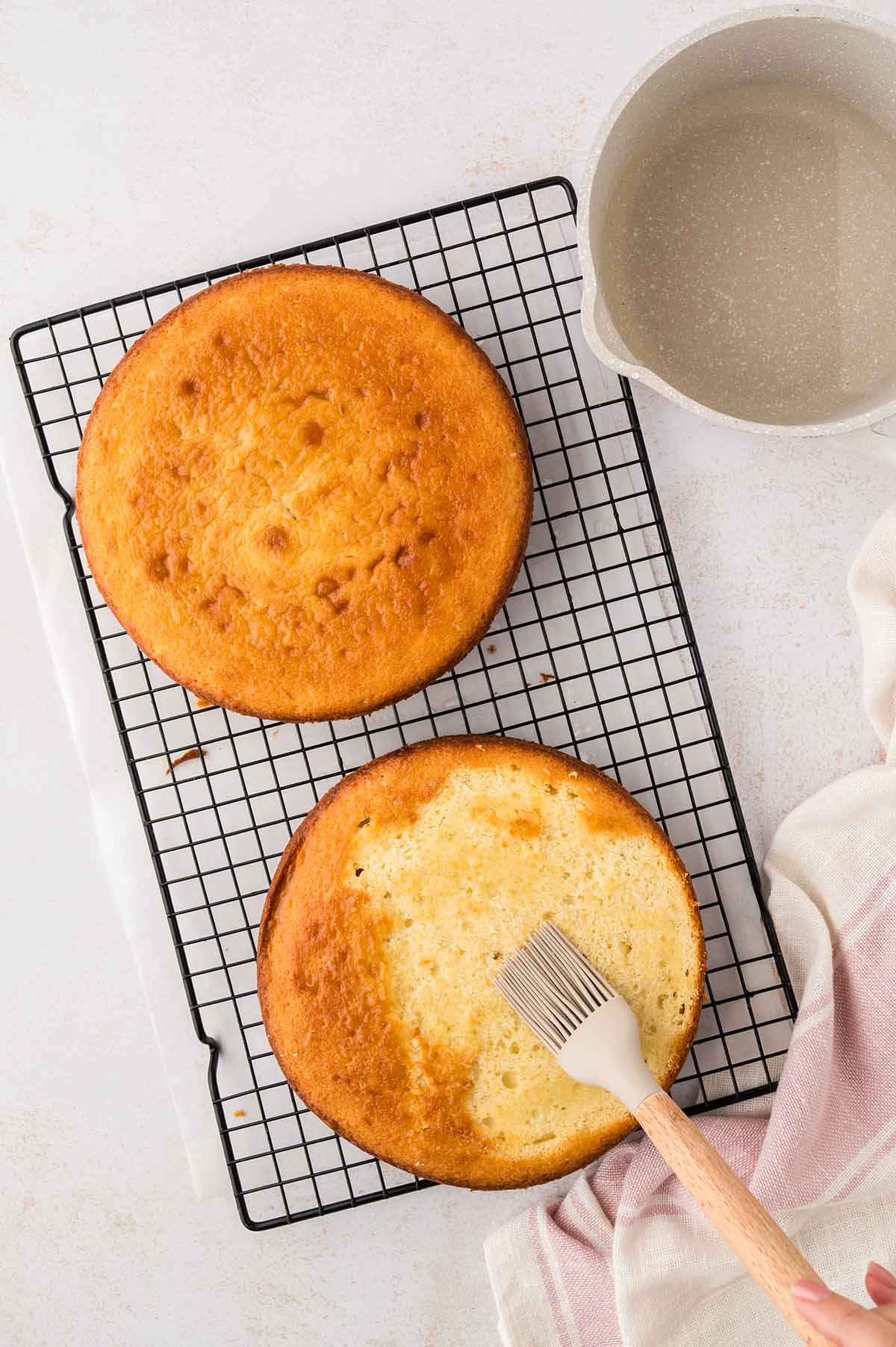 Simple syrup being brushed over the cake layers.