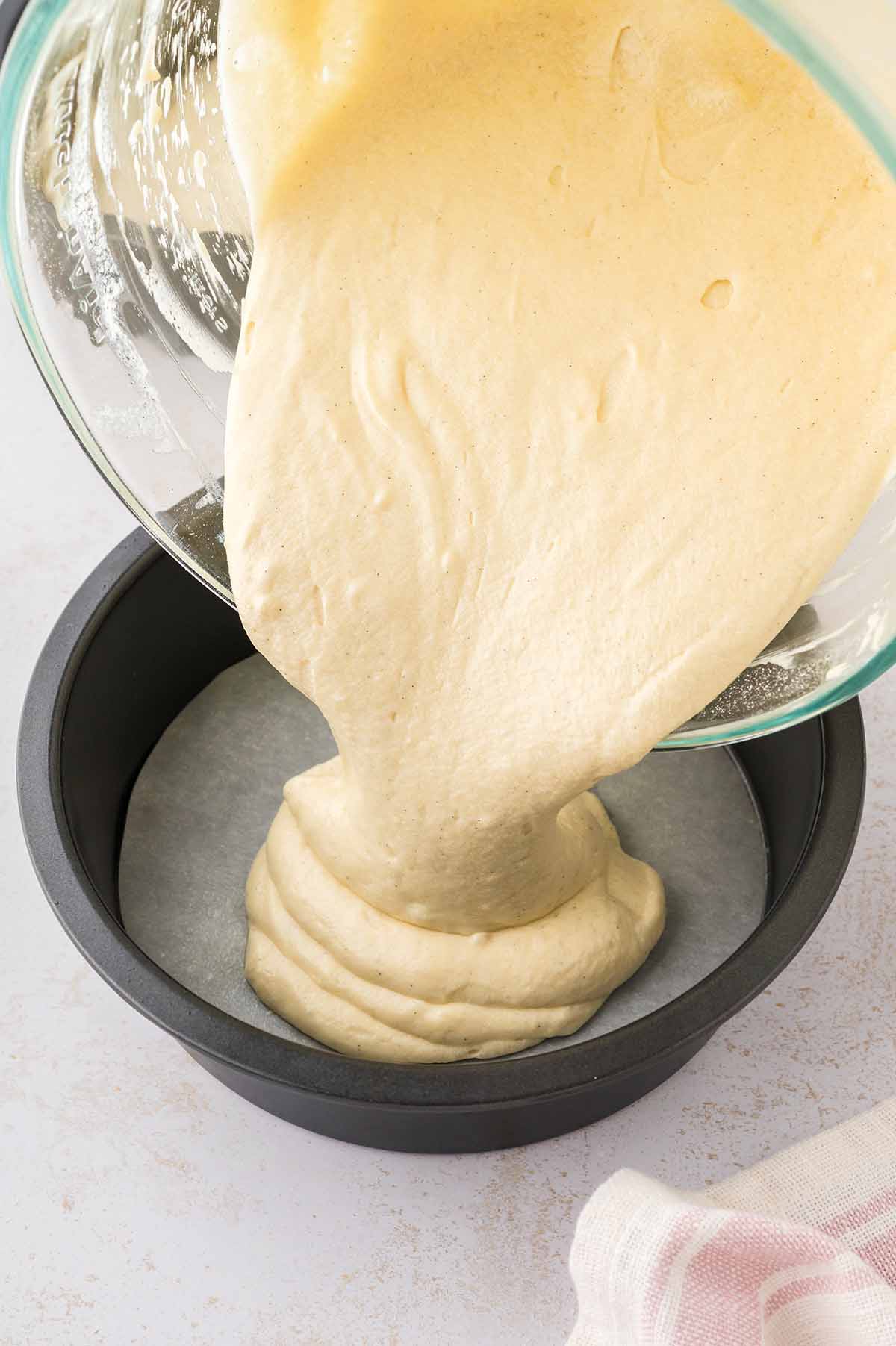 Cake batter being poured into a 9 inch cake pan.