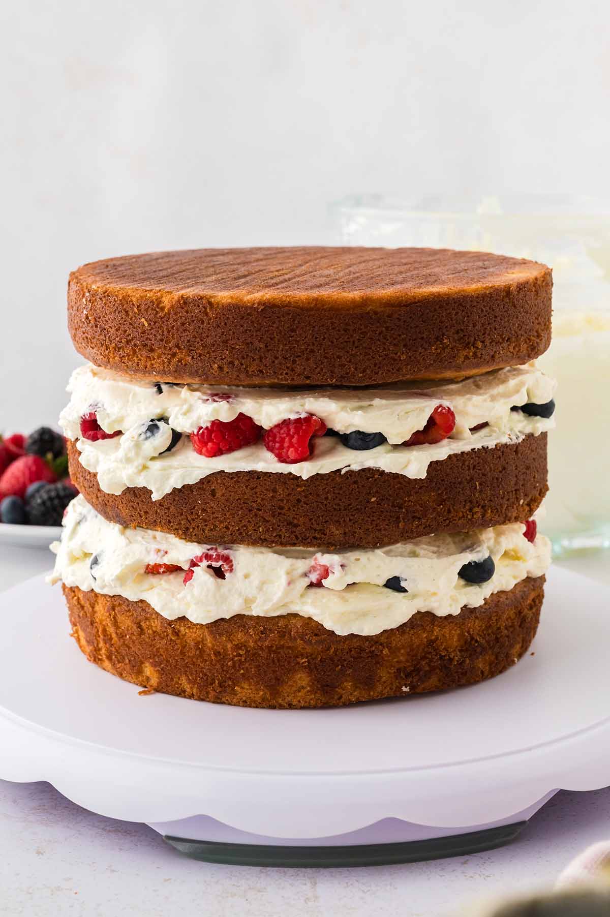 Three layer cake with frosting and berries in-between.