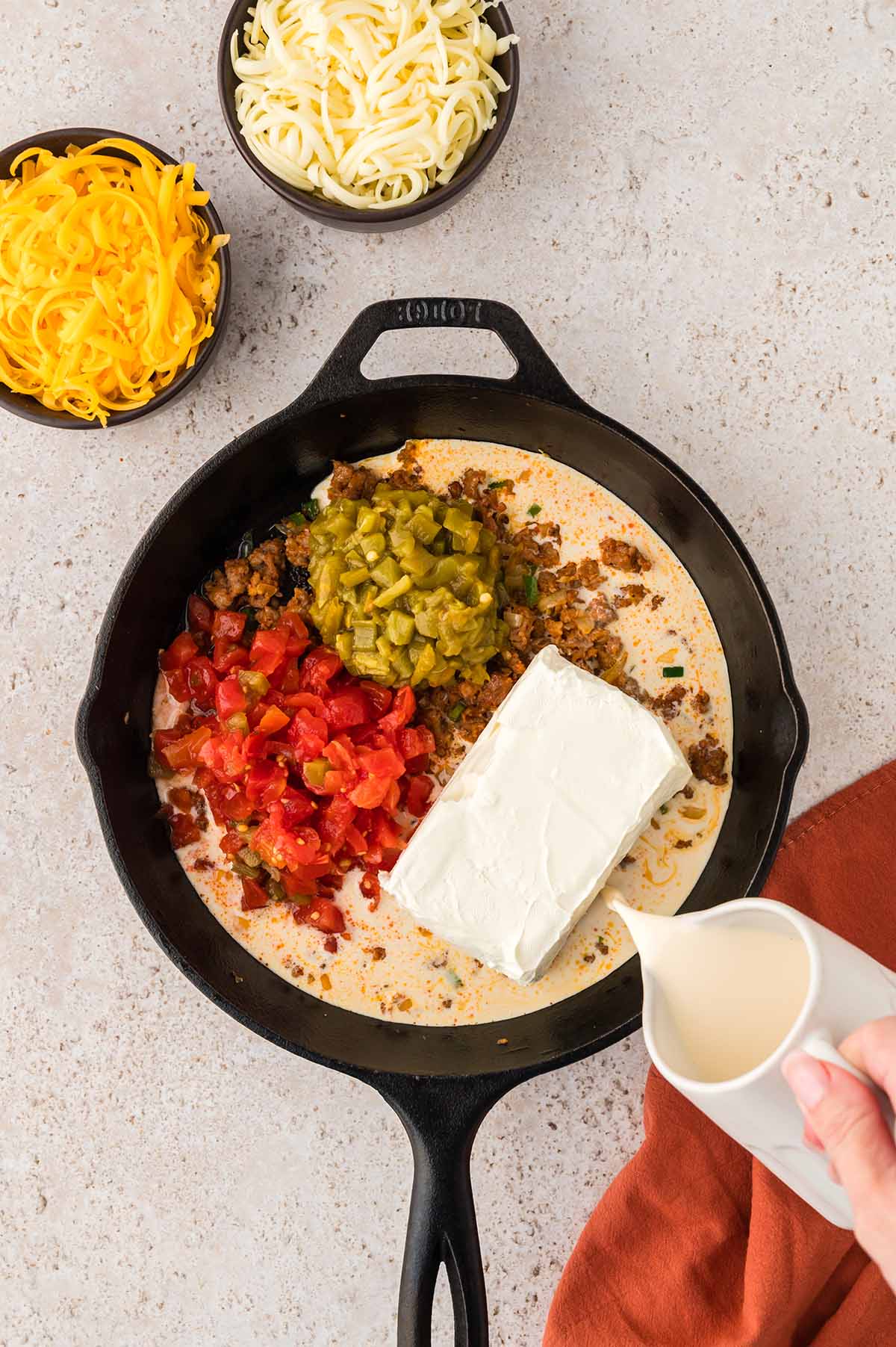 evaporated milk being poured into queso mixture.