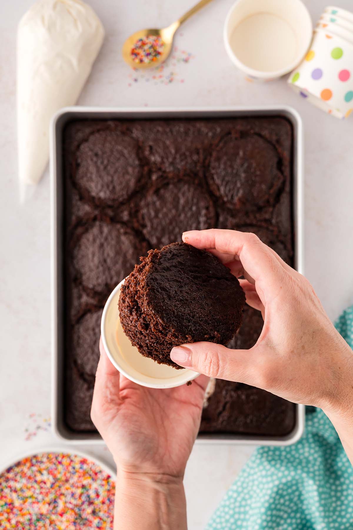 Hand placing a chocolate cake round into a paper cup.