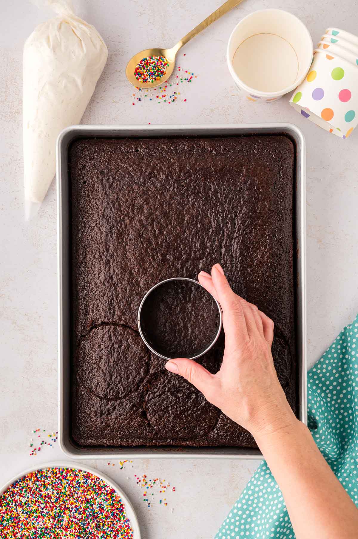 Round cookie cutter cutting circles from a chocolate cake.