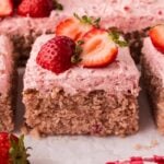 A slice of fresh strawberry cake with buttercream and fresh strawberries on top.