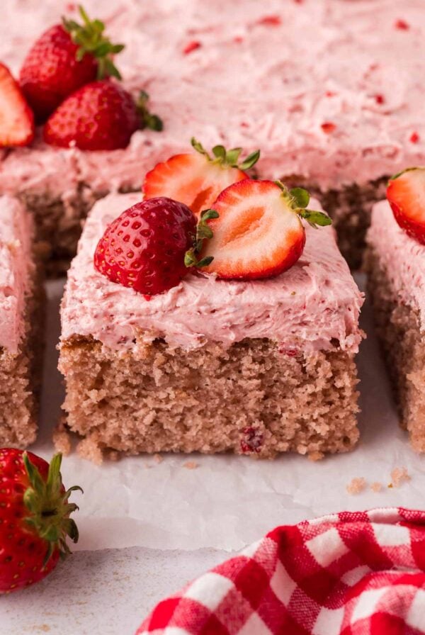 A slice of fresh strawberry cake with buttercream and fresh strawberries on top.
