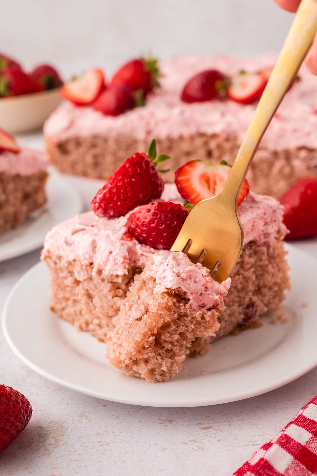 A gold fork cutting into a slice of cake.
