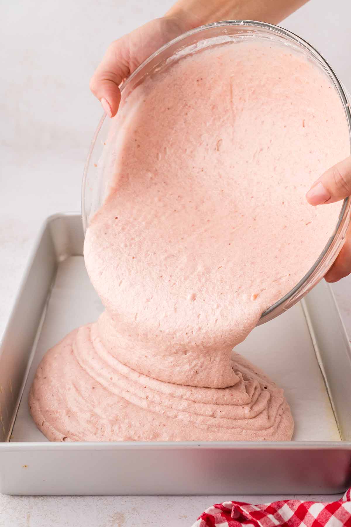 Cake batter being poured into a 9x13 baking dish.