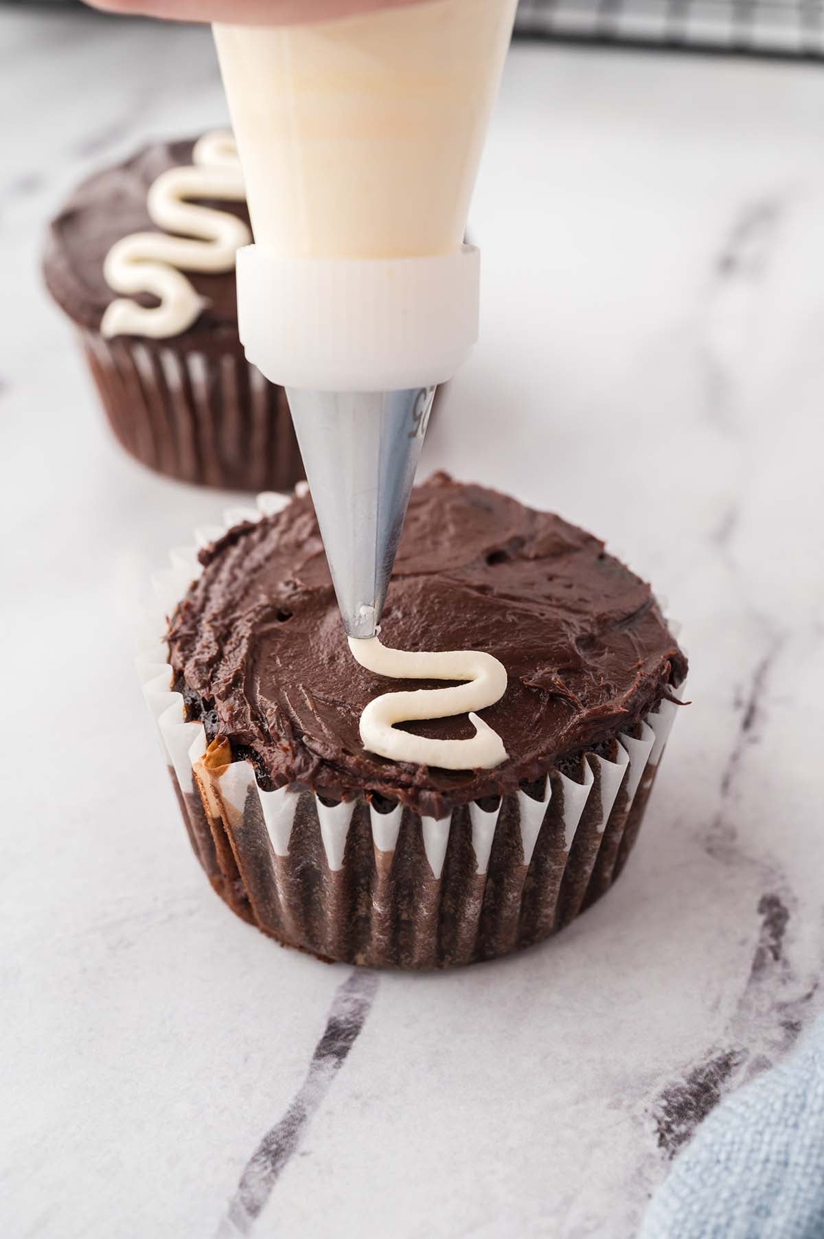 a piping bag to piping the signature white swirly line across the top of the cupcake.