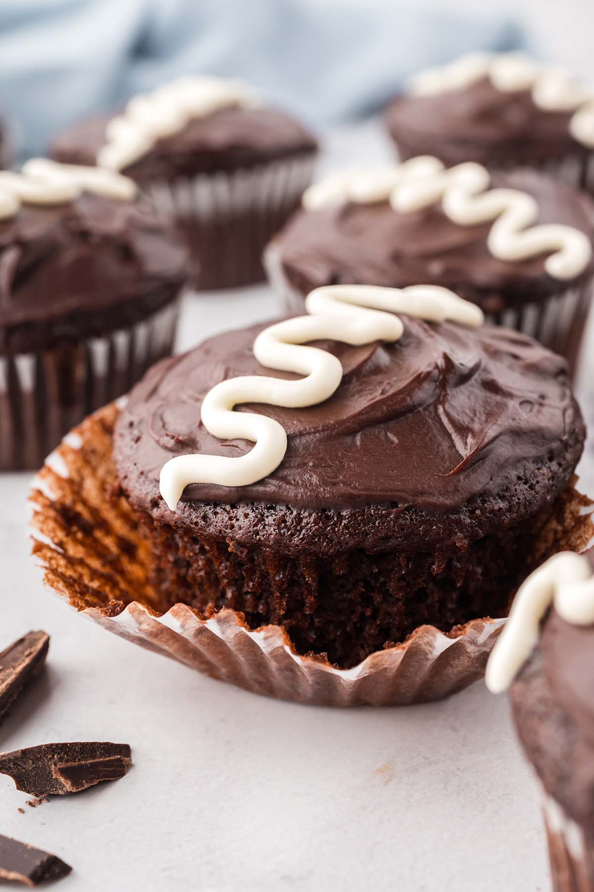 a chocolate cupcake with chocolate ganache and a white swirly line on top.