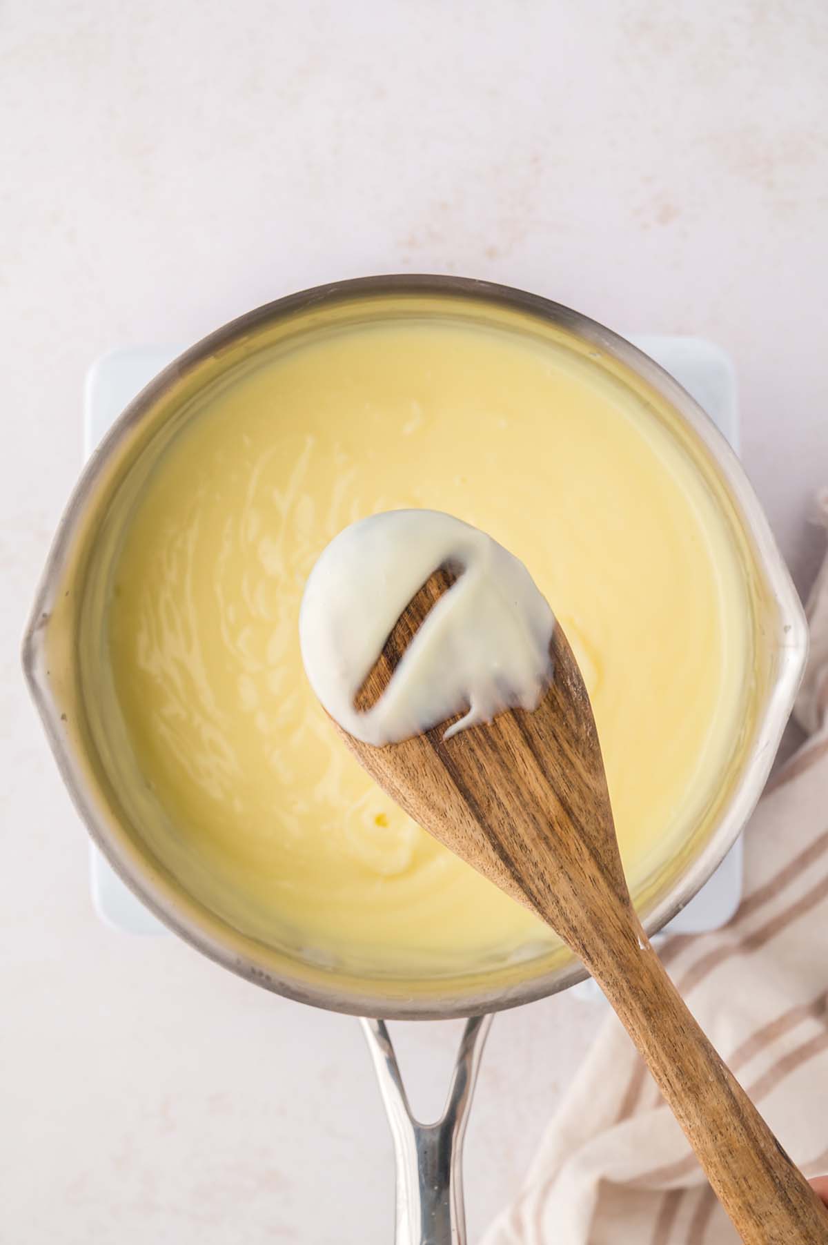 thick yellow custard in a saucepan with a wooden spoon.